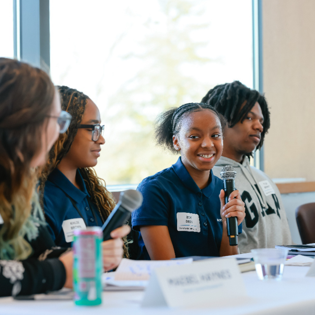 Junior Staff at conference speaking into microphone on a panel